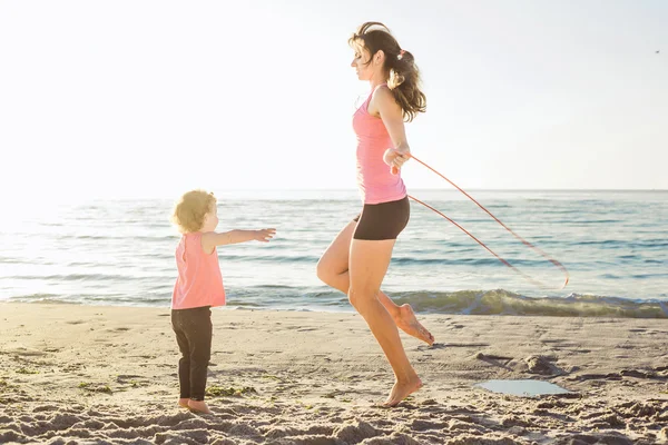 Сімейне тренування мати і дочка роблять вправи на пляжі . — стокове фото