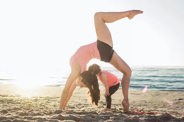 Aile egzersiz - anne ve kızı plajda egzersizleri yapıyor.