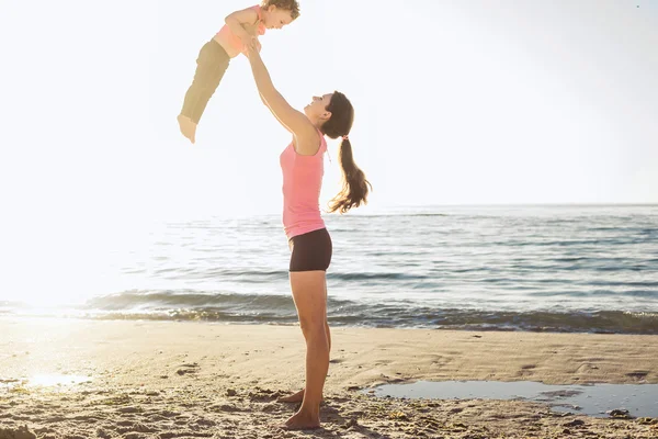 Familientraining - Mutter und Tochter machen Übungen am Strand. — Stockfoto