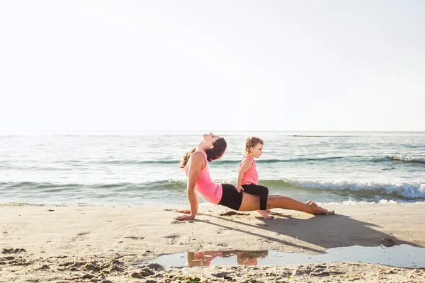 Séance d'entraînement en famille - mère et fille faisant des exercices sur la plage . — Photo