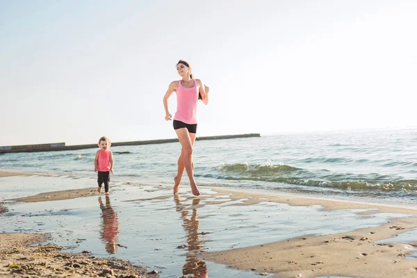 Séance d'entraînement en famille - mère et fille faisant des exercices sur la plage . — Photo