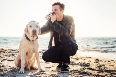 Genç beyaz erkek ile yürürken sahilde kahve içme