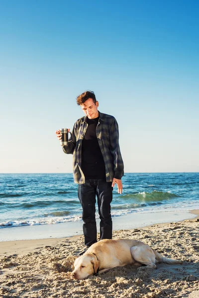 Młody mężczyzna kaukaski picia kawy na plaży podczas spaceru z — Zdjęcie stockowe