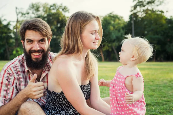 Молодая счастливая семья весело проводит время на свежем воздухе в парке — стоковое фото