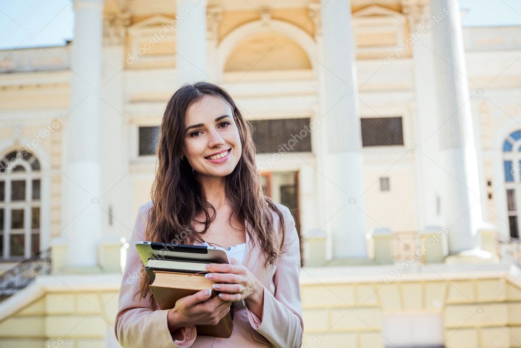 young caucasian female student with books and tablet on campus, student study in campus area