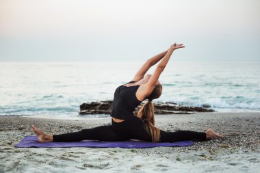 pratik Yoga plajda gündoğumu sırasında genç beyaz kadın