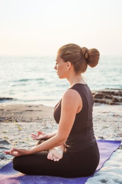pratik Yoga plajda gündoğumu sırasında genç beyaz kadın