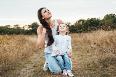 Anne ile birlikte, sonbahar sahada oynayan kız sevgi dolu aile açık havada eğlence