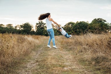 Anne ile birlikte, sonbahar sahada oynayan kız sevgi dolu aile açık havada eğlence