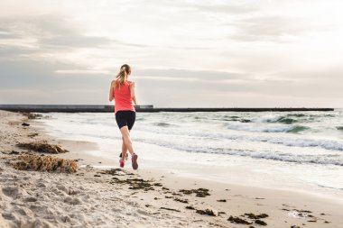 Fitness spor modeli gündoğumu üzerinde açık çalışması sırasında egzersizleri yapıyor. Güzel beyaz kadın eğitim dışında sahil sabah