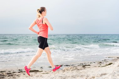 Fitness spor modeli gündoğumu üzerinde açık çalışması sırasında egzersizleri yapıyor. Güzel beyaz kadın eğitim dışında sahil sabah