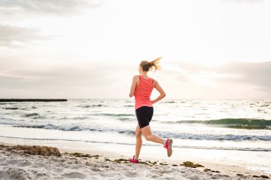 Fitness spor modeli gündoğumu üzerinde açık çalışması sırasında egzersizleri yapıyor. Güzel beyaz kadın eğitim dışında sahil sabah