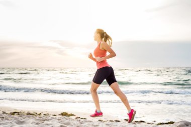 Fitness spor modeli gündoğumu üzerinde açık çalışması sırasında egzersizleri yapıyor. Güzel beyaz kadın eğitim dışında sahil sabah