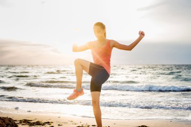Fitness spor modeli gündoğumu üzerinde açık çalışması sırasında egzersizleri yapıyor. Güzel beyaz kadın eğitim dışında sahil sabah