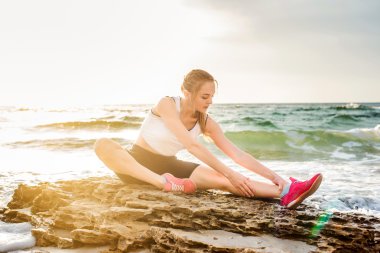 Fitness spor modeli gündoğumu üzerinde açık çalışması sırasında egzersizleri yapıyor. Güzel beyaz kadın eğitim dışında sahil sabah