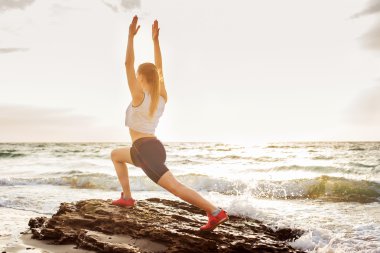 Fitness spor modeli gündoğumu üzerinde açık çalışması sırasında egzersizleri yapıyor. Güzel beyaz kadın eğitim dışında sahil sabah