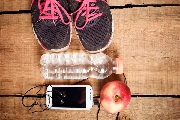 Equipamiento deportivo. Zapatillas, agua, manzana, despertador, smartphone y auriculares sobre fondo de madera. Ropa para correr. Concepto de mañana —  Fotos de Stock