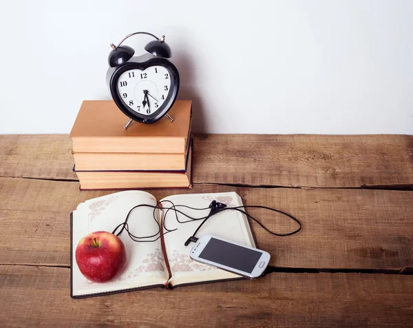 Książki, budzik, notatnik, cellphone rezygnować słuchawki i jabłko na drewniane tła. Sprzęt do edukacji, koncepcja edukacji — Zdjęcie stockowe