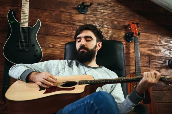 man playing guitar. Guitars on wall on background, love music concept