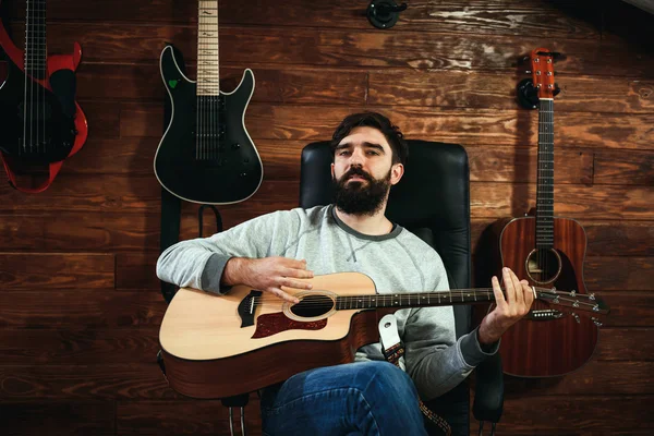 man playing guitar. Guitars on wall on background, love music concept