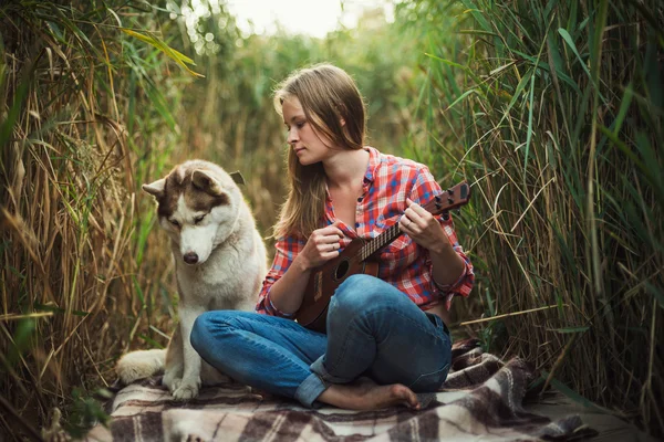 Genç Kafkas kadın iskambil gitar. Erkek ile açık havada gitar çalmak Sibirya husky köpek