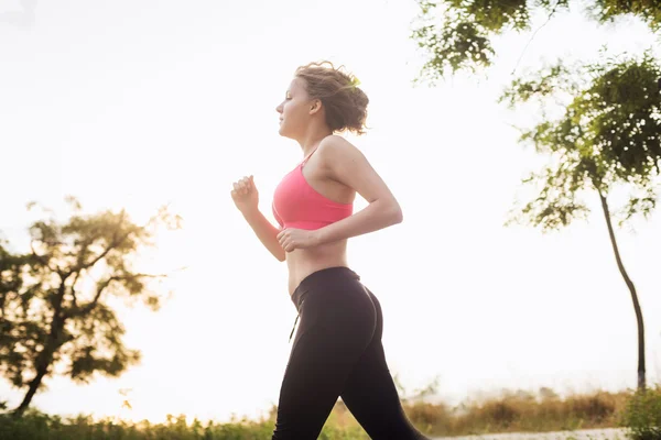 Systemem kobieta. Kobiece kobieta lekkoatletka joggingu podczas sunrise — Zdjęcie stockowe
