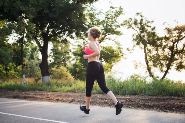 Systemem kobieta. Kobiece kobieta lekkoatletka joggingu podczas sunrise — Zdjęcie stockowe