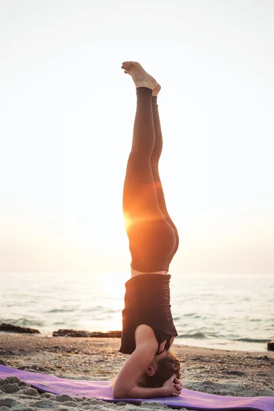 Junge kaukasische Frau praktiziert Yoga am Strand bei Sonnenaufgang — Stockfoto