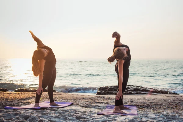 Dwie młode kobiety kaukaski praktykowania jogi na plaży podczas sunrise — Zdjęcie stockowe