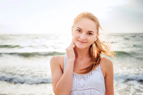 Joven hermosa hembra caucásica disfrutando del sol en la playa al amanecer o al atardecer — Foto de Stock