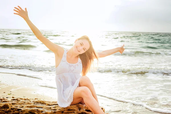 Jovem bela mulher caucasiana desfrutando do sol na praia durante o nascer do sol ou pôr do sol — Fotografia de Stock