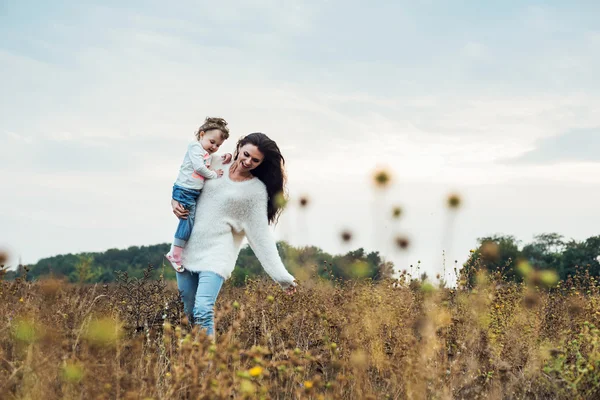 Mother and daughter playing on autumn field — Stock Photo, Image