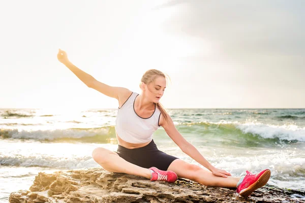 Model sport fitness robienie ćwiczeń podczas pracy na zewnątrz na wschód. Piękny kaukaski kobiece szkolenia poza nad morzem rano — Zdjęcie stockowe