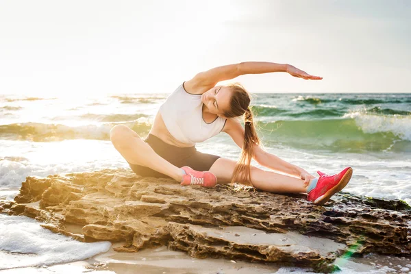 Fitness spor modeli gündoğumu üzerinde açık çalışması sırasında egzersizleri yapıyor. Güzel beyaz kadın eğitim dışında sahil sabah