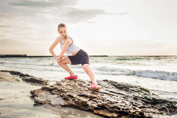 Model sport fitness robienie ćwiczeń podczas pracy na zewnątrz na wschód. Piękny kaukaski kobiece szkolenia poza nad morzem rano — Zdjęcie stockowe