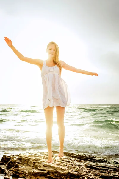 Young beautiful caucasian female enjoying the sun on beach during sunrise or sunset Stock Photo