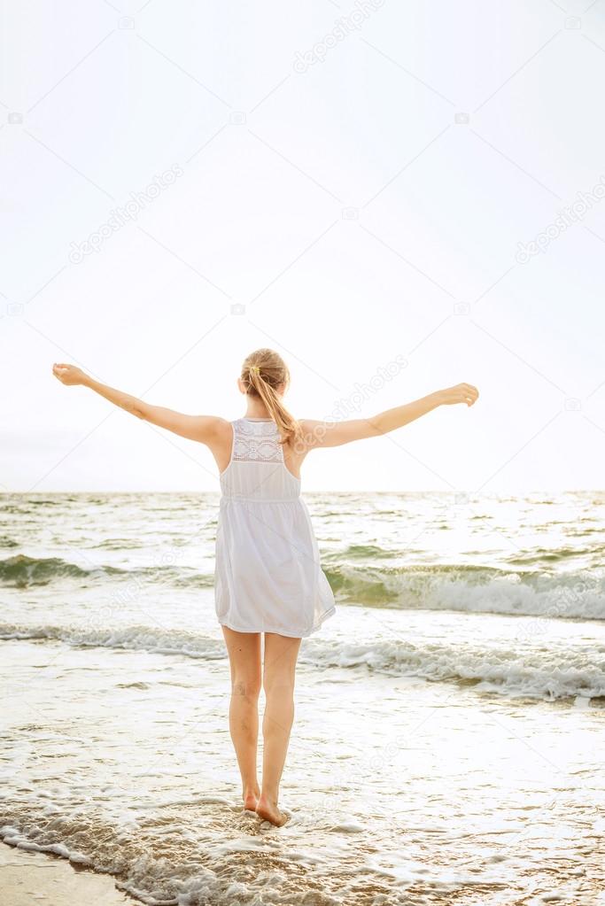 young beautiful caucasian female enjoying the sun on beach during sunrise or sunset