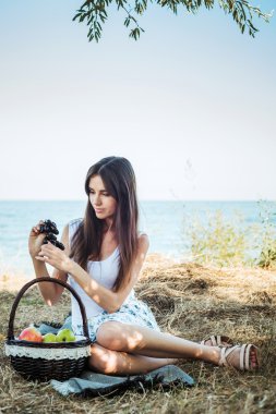 ile meyve sepeti ile sahil üzerinde genç beyaz kadın. Yeme meyve, sağlıklı beslenme ve sağlıklı yaşam kavramı kız