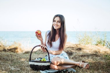 ile meyve sepeti ile sahil üzerinde genç beyaz kadın. Yeme meyve, sağlıklı beslenme ve sağlıklı yaşam kavramı kız