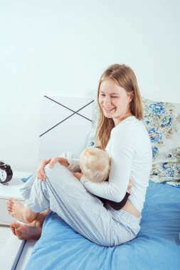 kadın emzirme çocuğunu yatağın üstüne oturuyor