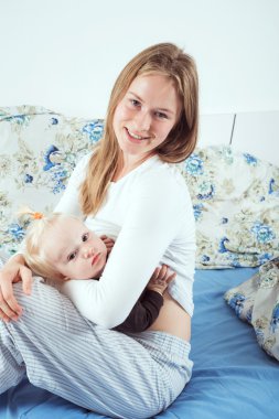 kadın emzirme çocuğunu yatağın üstüne oturuyor