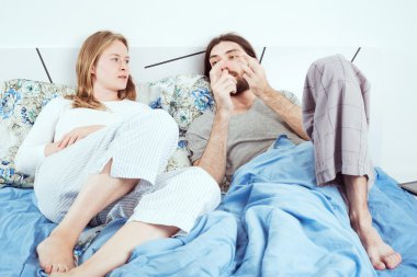 Genç sevgili çift gülümseyen ve yatakta konuşuyor