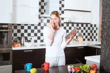 elma ve tablet ile mutfak üzerinde genç beyaz kadın. Mutfak tablet tarifleri sağlıklı gıda üzerinde arama kadınlarda. Yemek sebze ve meyve ile sağlıklı yemek