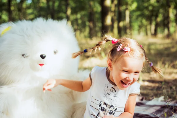 Pequena menina bonita brincando com grande urso branco brinquedo no parque — Fotografia de Stock