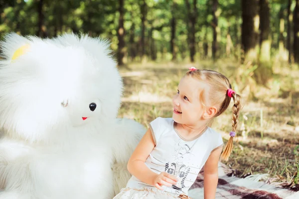 Niña bonita jugando con gran oso blanco juguete en el parque — Foto de Stock