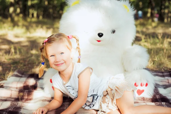 Niña bonita jugando con gran oso blanco juguete en el parque — Foto de Stock