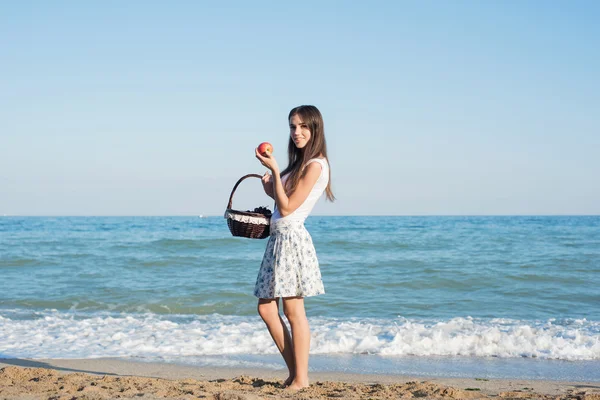Junge kaukasische Hündin mit Halterung mit Äpfeln und Früchten am Strand. gesundes Leben und gesunde Ernährung — Stockfoto