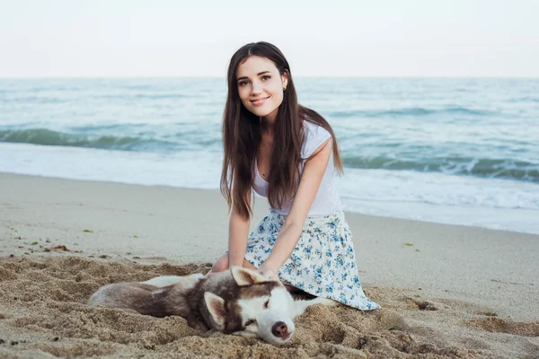 Joven caucásico hembra jugando y divertirse con siberiano husky perro en playa —  Fotos de Stock