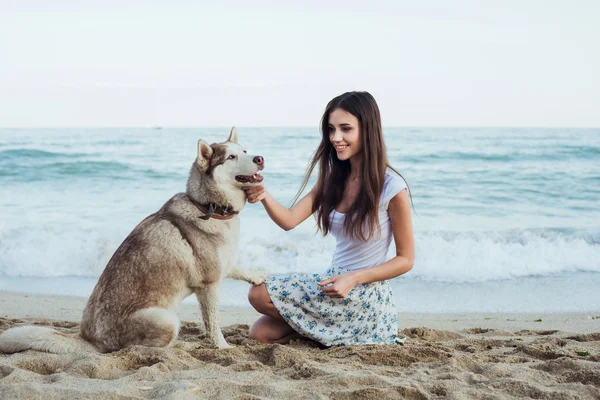 Młody kaukaski kobiece gry i zabawy z psem husky syberyjski na plaży — Zdjęcie stockowe