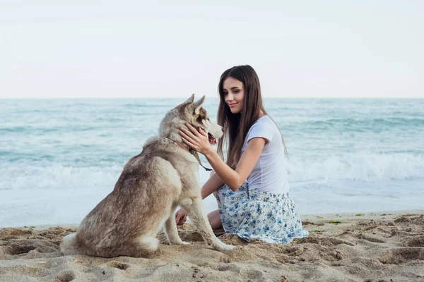 Junge kaukasische Hündin spielt und amüsiert sich mit sibirischem Husky-Hund am Strand — Stockfoto